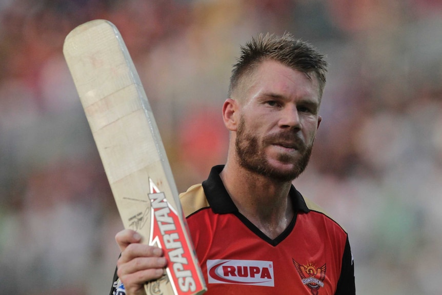 Bearded cricketer raises his bat in salute to the crowd.