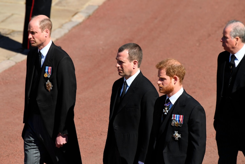Prince William and Prince Harry walk behind Prince Philip's coffin with another man between them.
