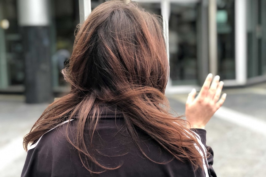 A woman with dark hair, face unseen