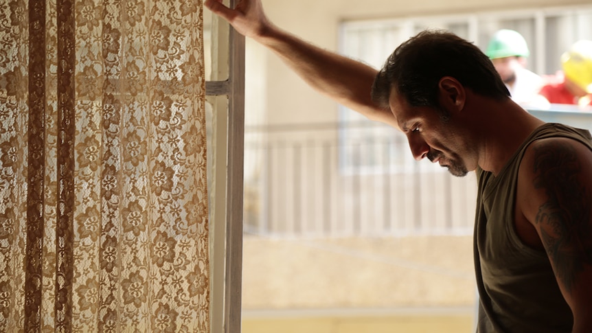 Still image of Adel Karam leaning against a window still and looking down in 2018 film The Insult.