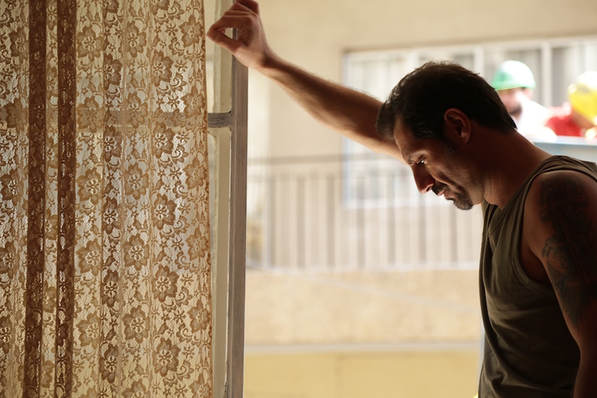 Still image of Adel Karam leaning against a window still and looking down in 2018 film The Insult.