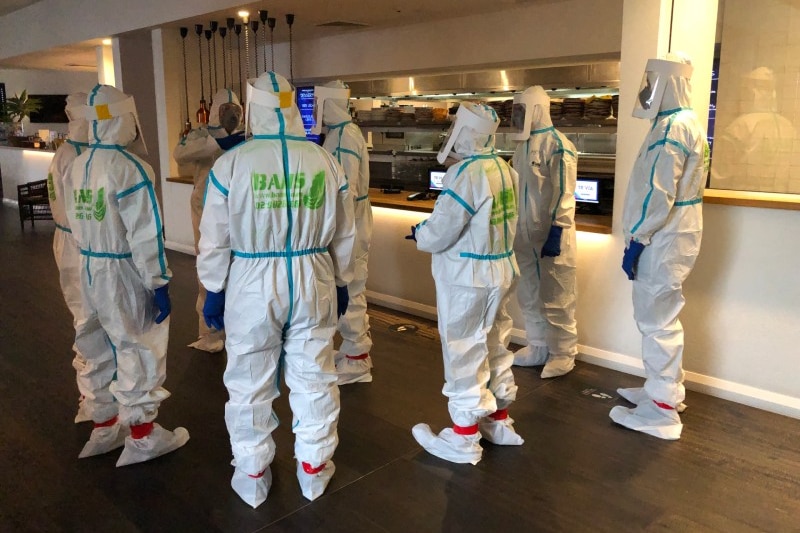 A group in hazmat suits in an empty hotel kitchen area.