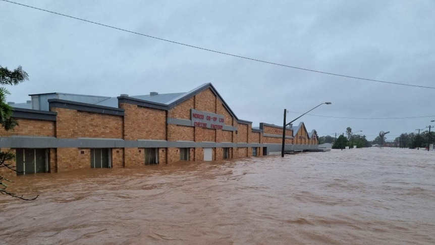 A historic brick industrial building is inundated by more than a metre of brown flood water.