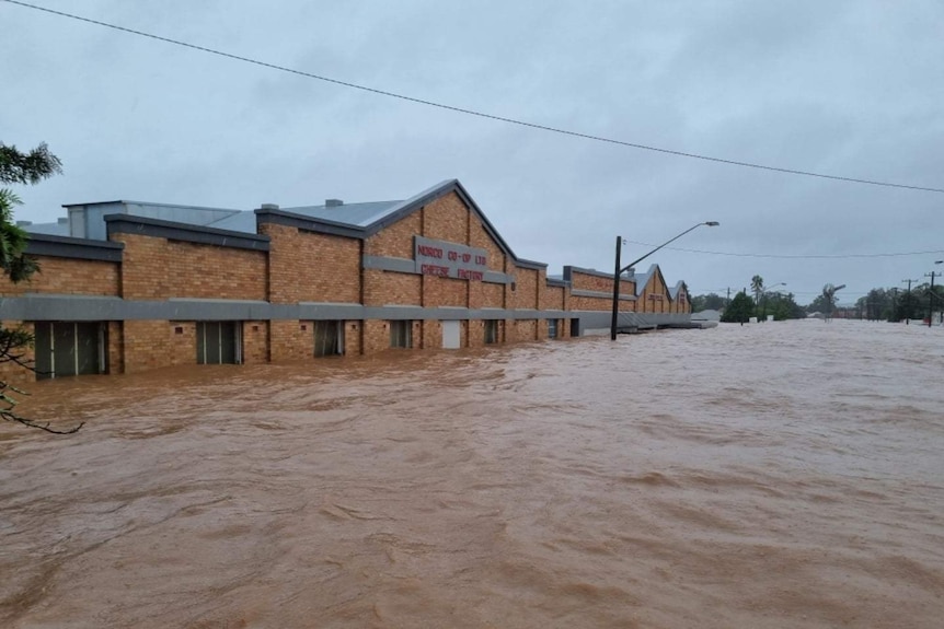 A historic brick industrial building is inundated by more than a metre of brown flood water.