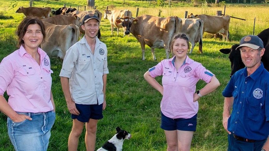 A family of four with cows behind them.