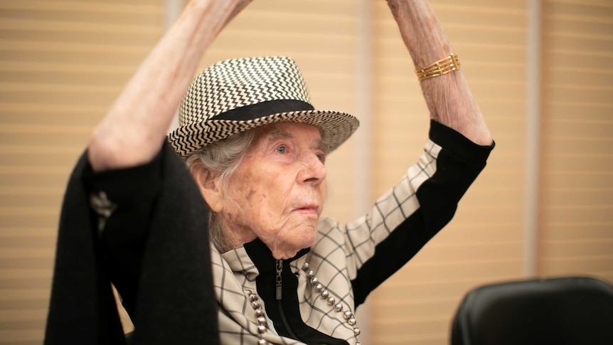 Class participant X holds her arms above her head.