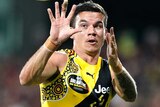 A Richmond Tigers AFL player holds out his two hands as he looks to catch the ball against Essendon.