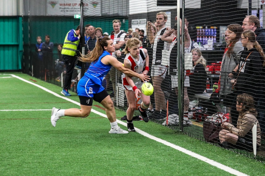 Two players jostle for the ball while spectators look on.