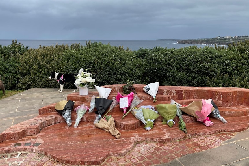 Flowers are laid upon a series of steps overlooking the coastline in Bondi.