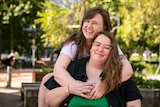 Freya, left, wraps her arms around Bec, right bottom, as they both beam while posing in a public park.