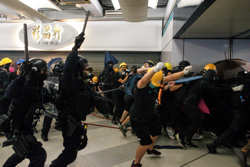 Special Tactical Squad officers attack protesters with batons inside a train station.