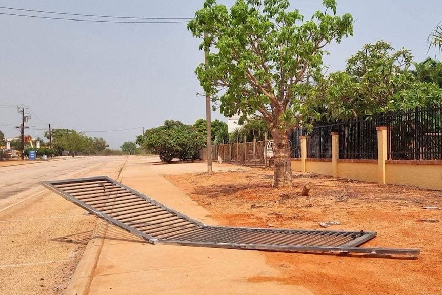 A large metal fence lies on a footpath.