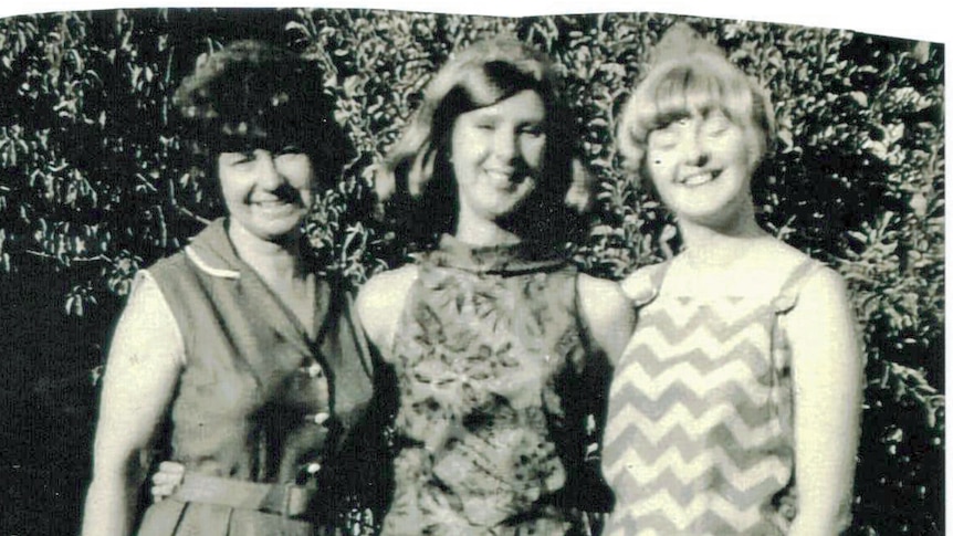 A black and white photo of three woman wearing dresses.