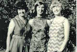A black and white photo of three woman wearing dresses.