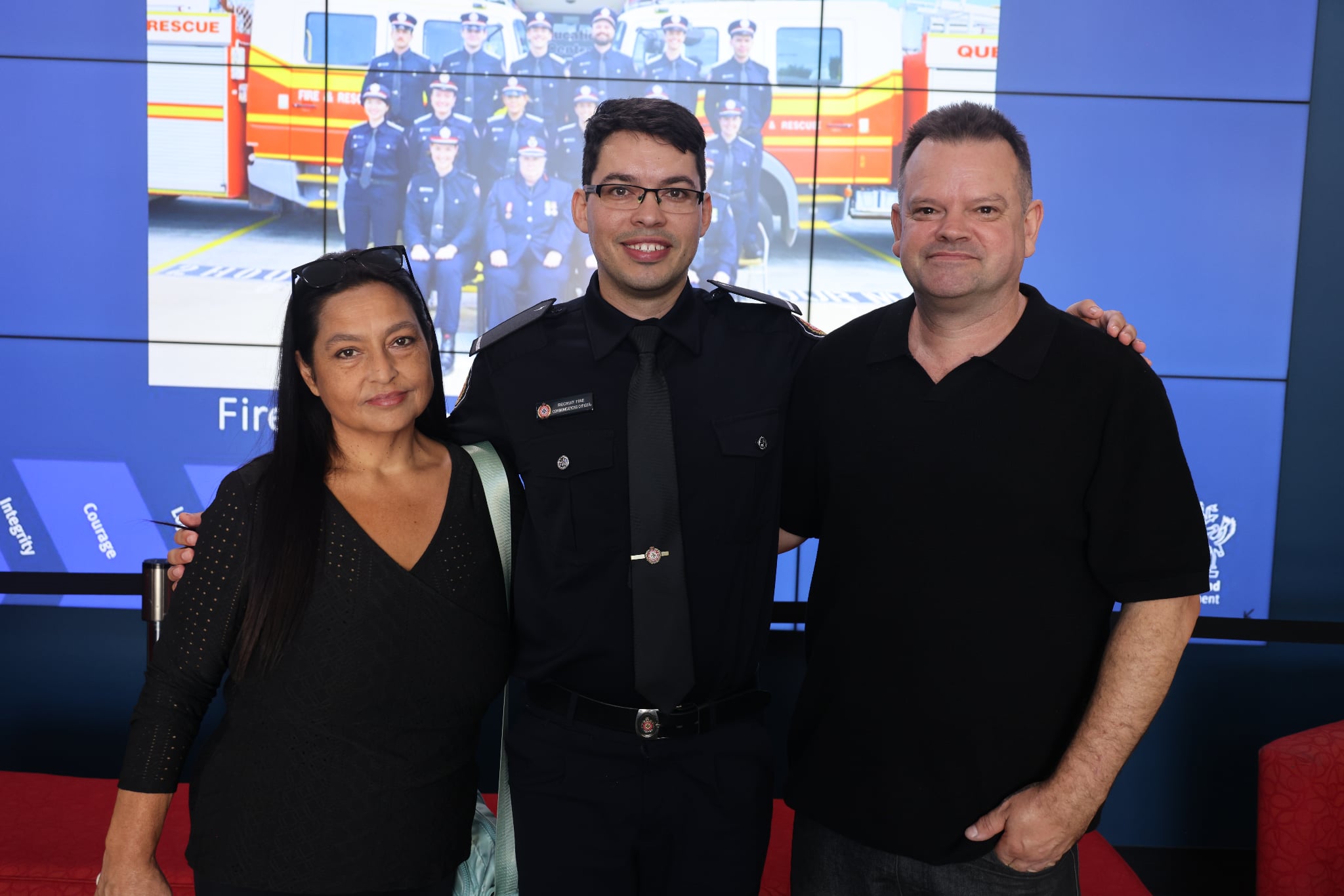 Tyler Pask abraçou a mãe (à esquerda) e o pai (à direita) em sua formatura como oficial de comunicações da QFS.