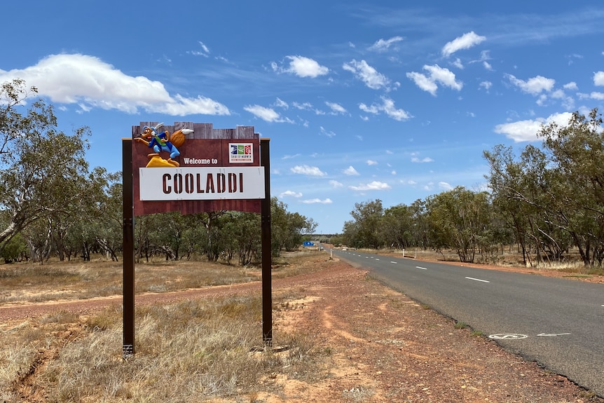 A sign reads "Welcome to Cooladdi" on the side of a road.