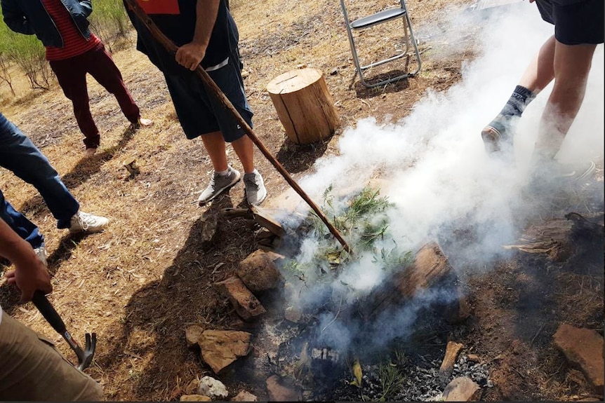 A man stokes a fire with a stick