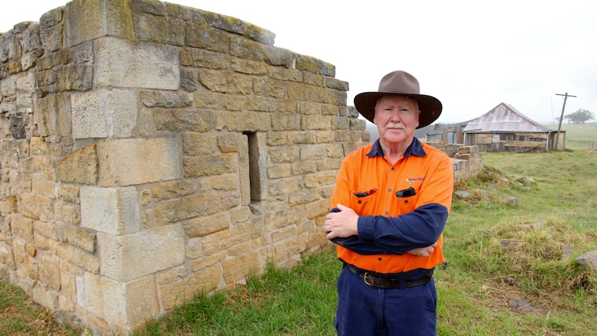 Kel Lambkin Water NSW Heritage Officer stands next to an historic stone granary at the Windmill Hill heritage site.