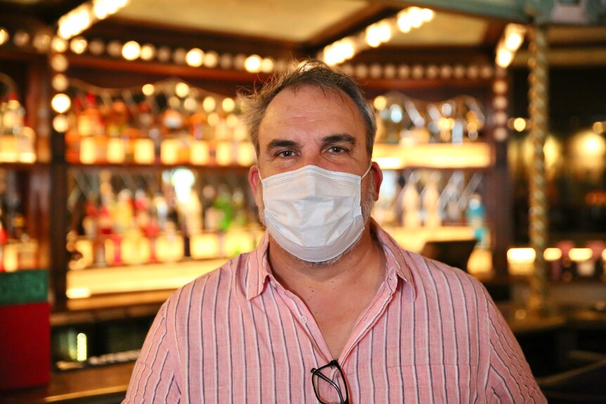 A close-up of David Heaton wearing a mask standing in his bar.