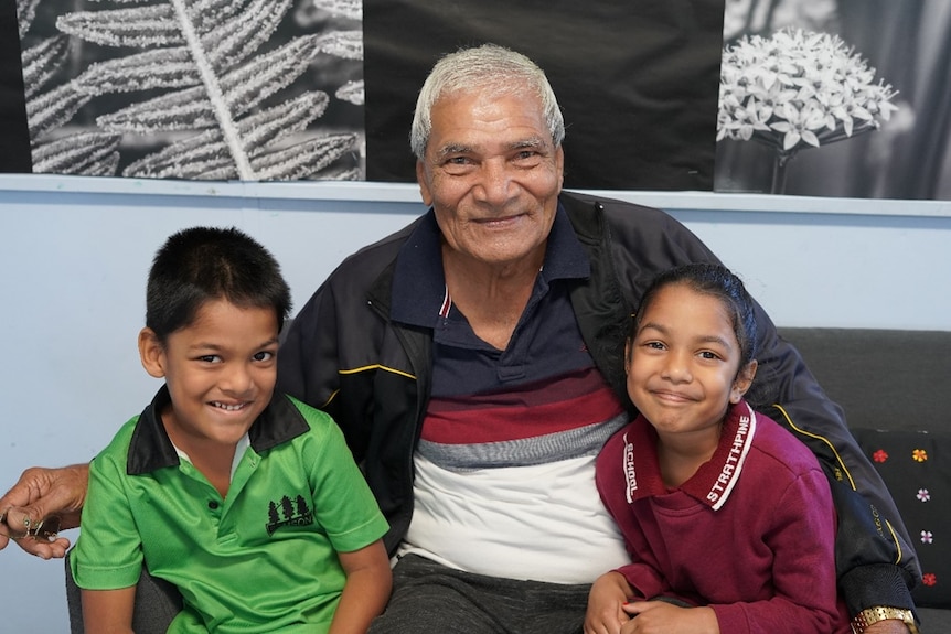 Grandfather Narran Om sits with his twin grandchildren Hely and Hian.