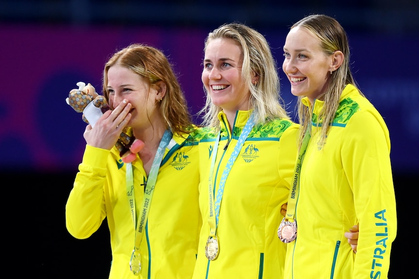 Three women stand in a line smiling