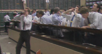 A man speaks on the phone inside wall st while other brokers look on in shock