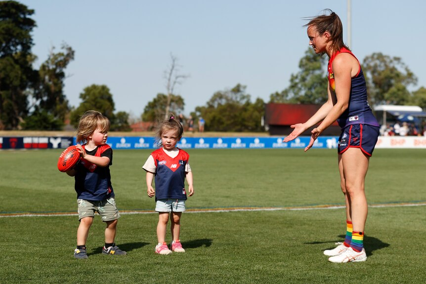 AFLW Melbourne Demons player Daisy Pearce asks for the ball from one of her two kids on the field after a game.
