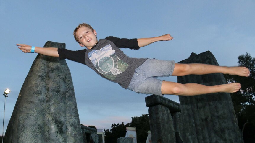 Boy plays on Sacrilege, an inflatable Stonehenge replica