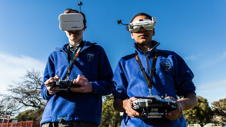 Teenage drone teachers Cale Manly, 15 (left) and Nathaniel  Kuchel, 16 wearing goggles and holding controls.