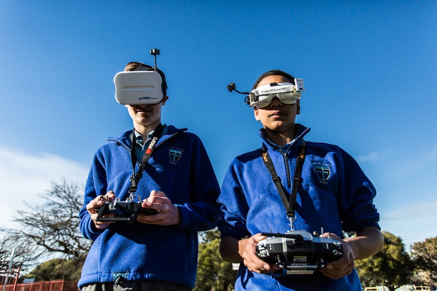 Teenage drone teachers Cale Manly, 15 (left) and Nathaniel  Kuchel, 16 wearing goggles and holding controls.