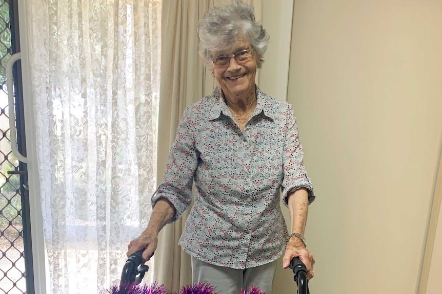 A woman stands with a walking frame.