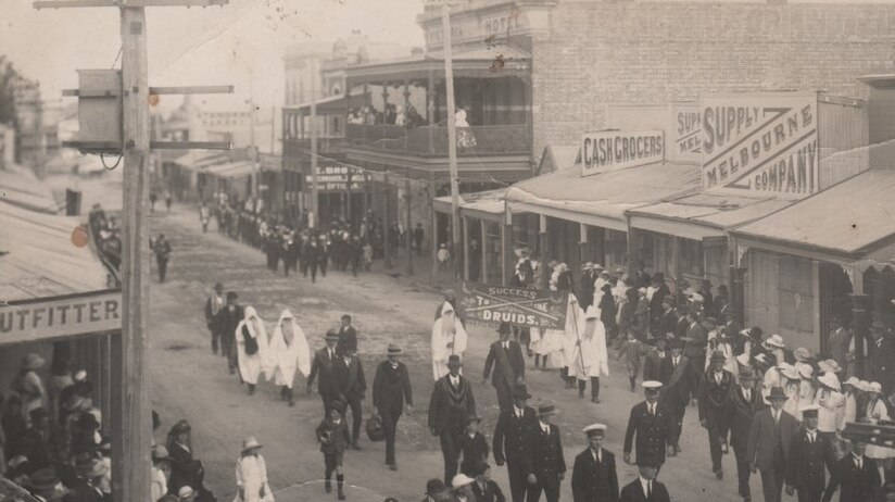Historic shot of a Druids march down a main street of a country town.