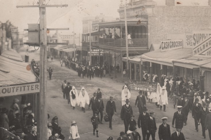 Historic shot of a Druids march down a main street of a country town.