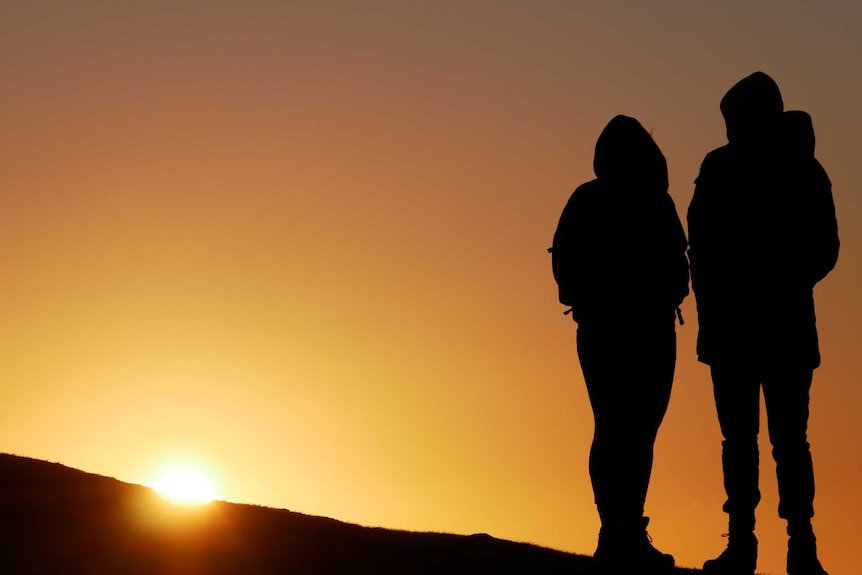 Silhouette of a couple with setting sun in background