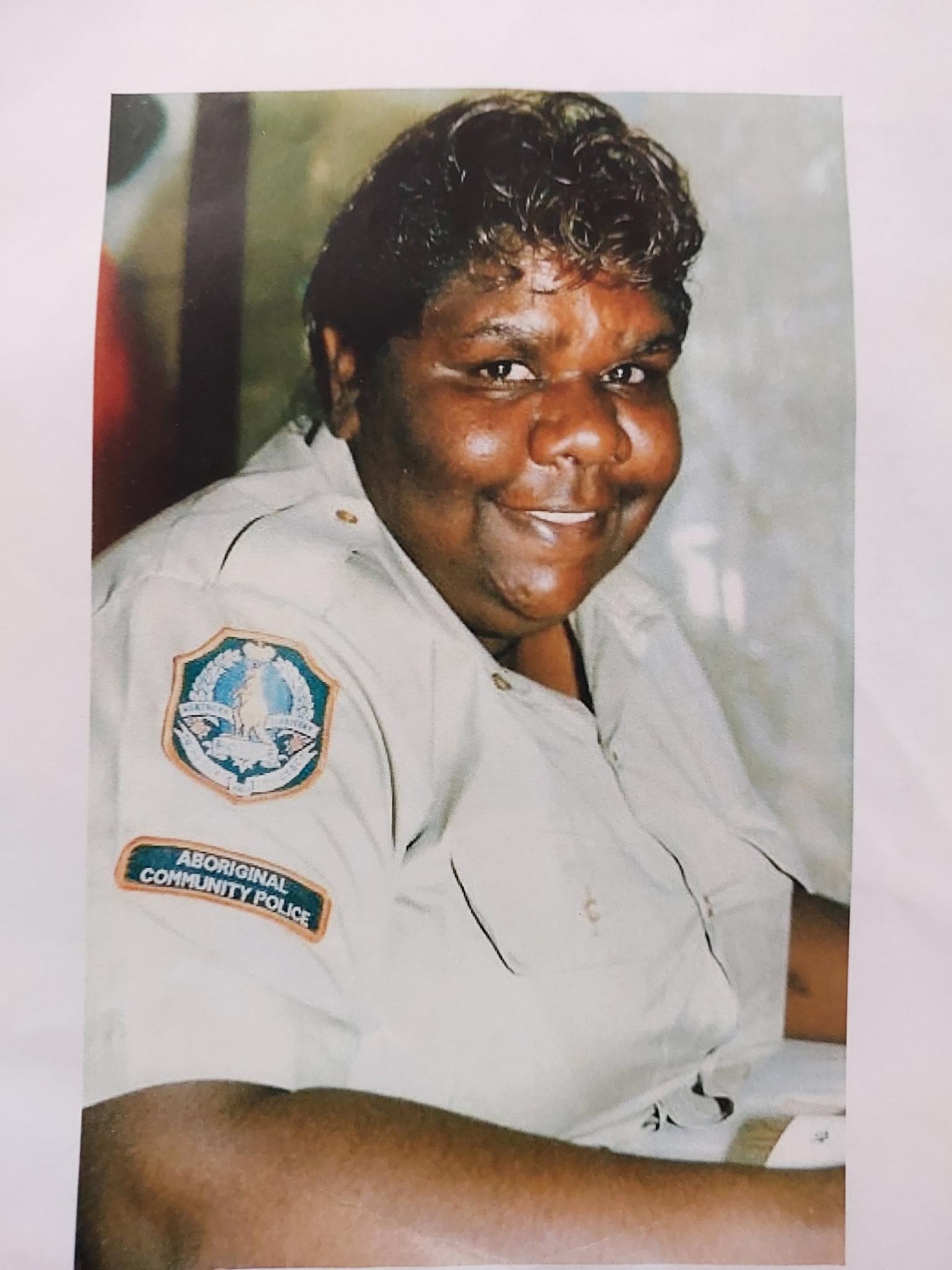 An Indigenous woman in a police uniform smiles at the camera.