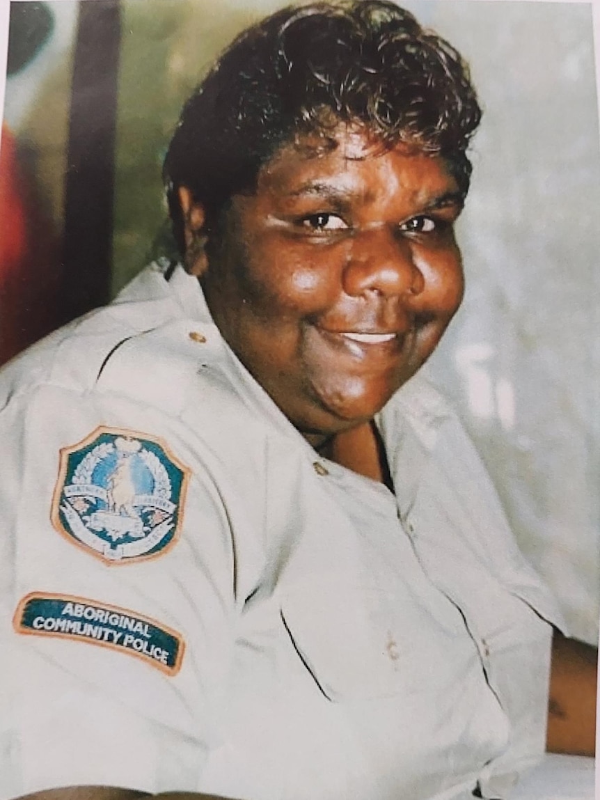 An Indigenous woman in a police uniform smiles at the camera.