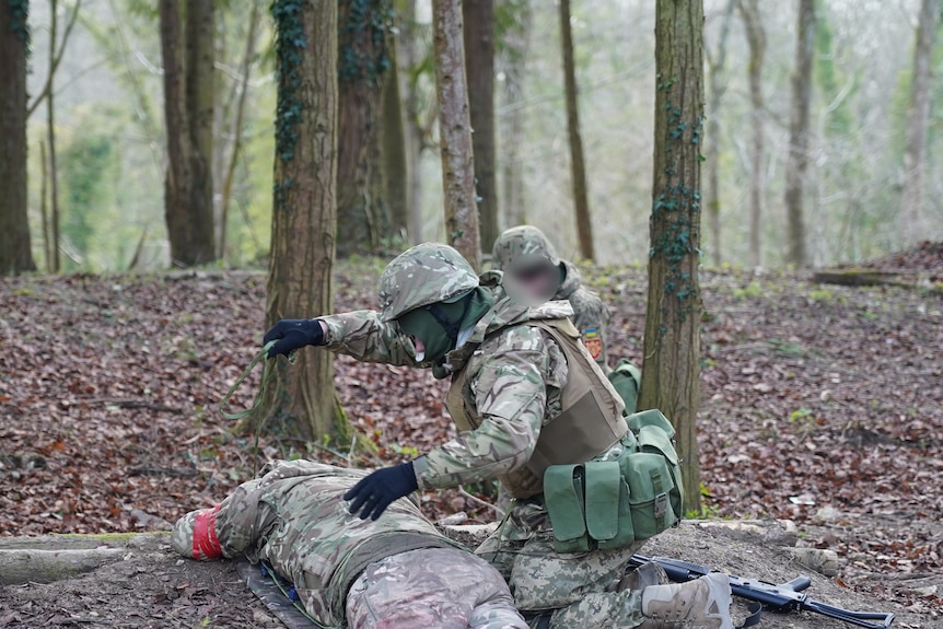 Two uniformed troops crouch over a doll fashioned to represent a fallen comrade.