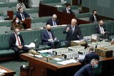 Scott Morrison points at the opposition, with several ministers sitting socially distanced on a bench behind him, wearing masks.