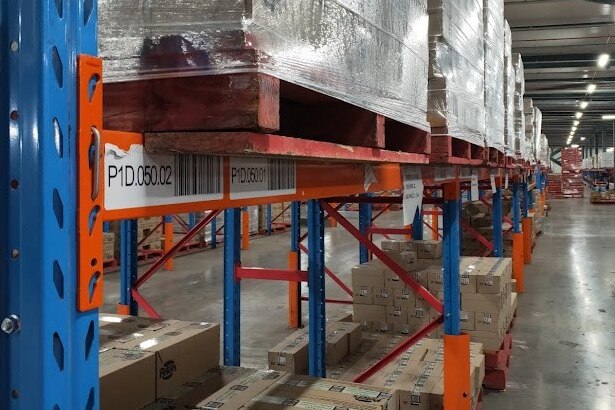 A picture of hundreds of boxes on storage shelves in a warehouse with cold lighting. 