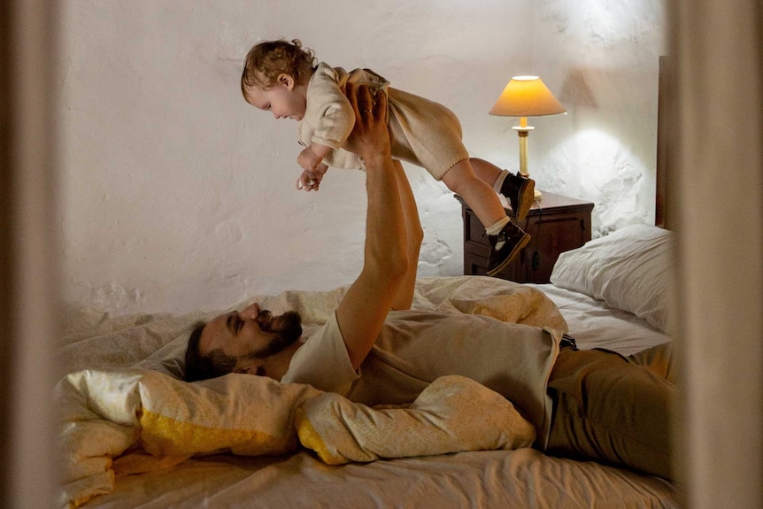 Dad holding childing up in bed