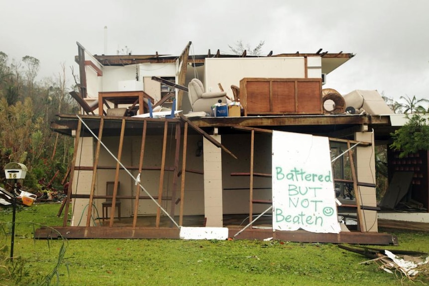 A house in Tully after cyclone Yasi with a hand made sign - battered but not beaten