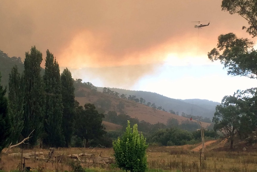 A firefighting helicopter flies into smoke from the fire at Dargo.