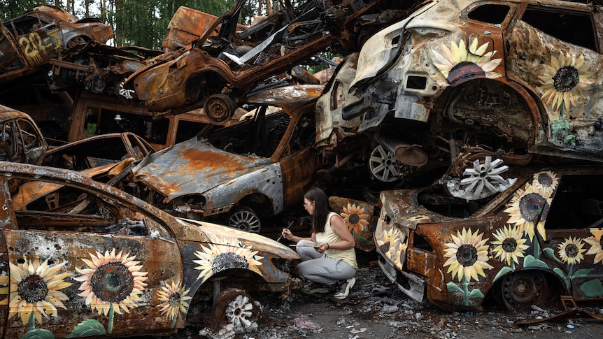 A Ukrainian artist Olena Yanko paints sunflowers on cars which were destroyed by Russian attacks in Irpin.
