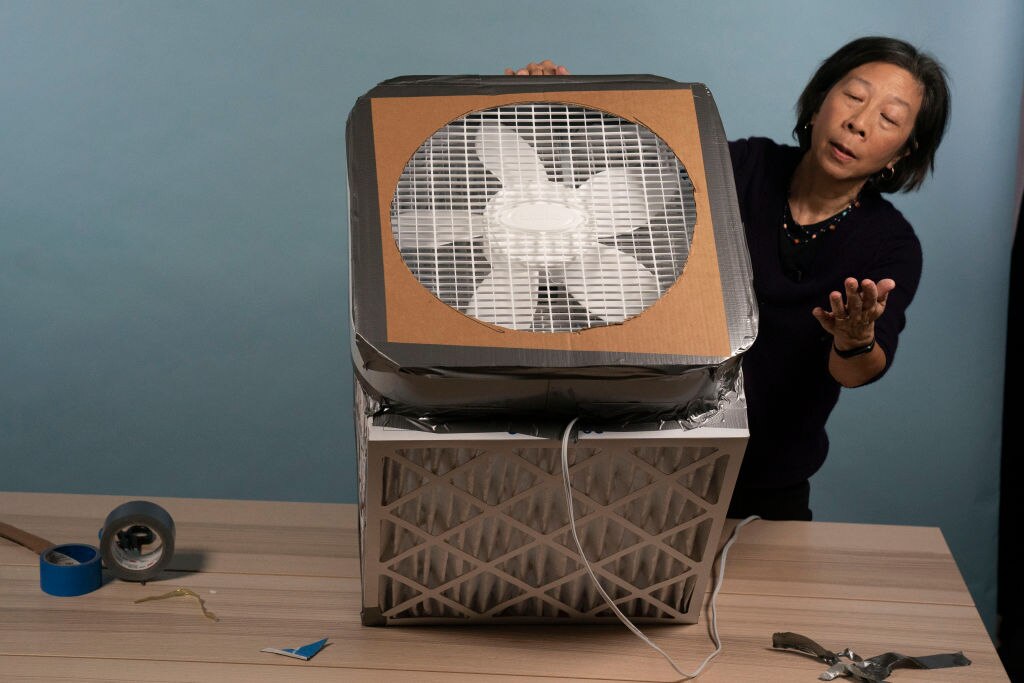 A woman showing an example of a DIY air purifying unit made in the US.