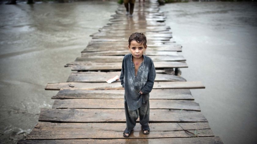 A Pakistani child stands on a wooden bridge surrounded by floodwaters (Behrouz Mehri: AFP)