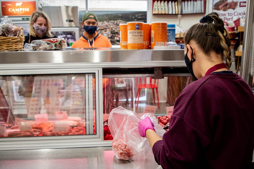 A staff member packages meat for Michelle and Enrique Torino who wait behind the counter at Campisi Butchery in Liverpool.