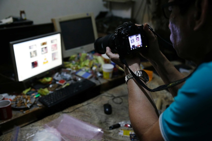 A Filipino police investigator takes a picture of the computer of a suspected child sexual exploitation operator