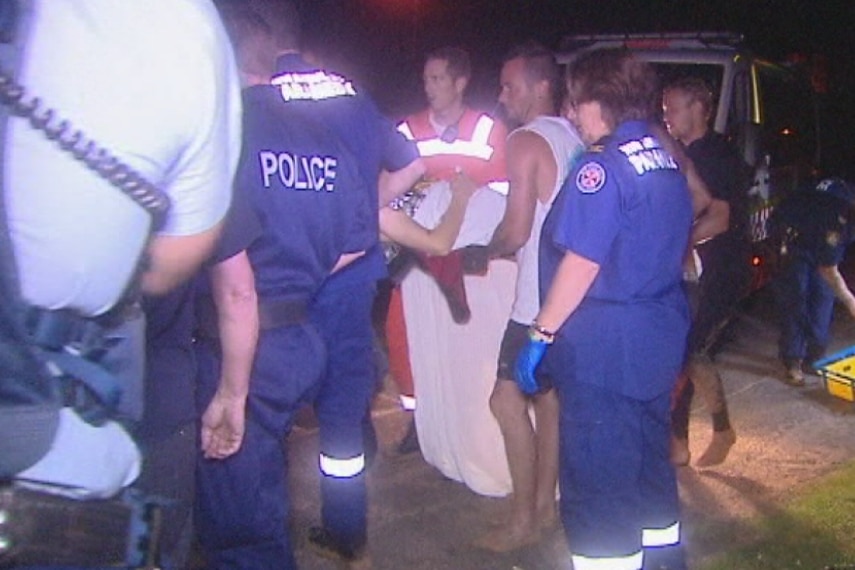 Paramedics, police and others help carry the victim on a stretcher.