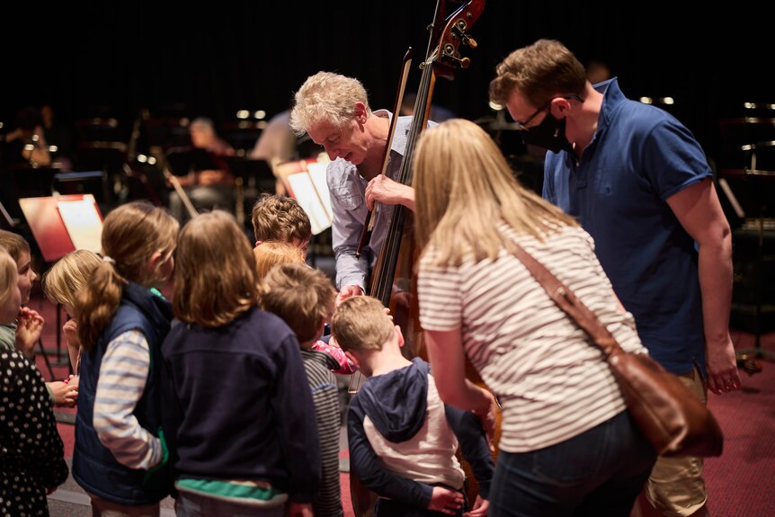Young audience members at a Relaxed concert gather around an ASO double bassist.