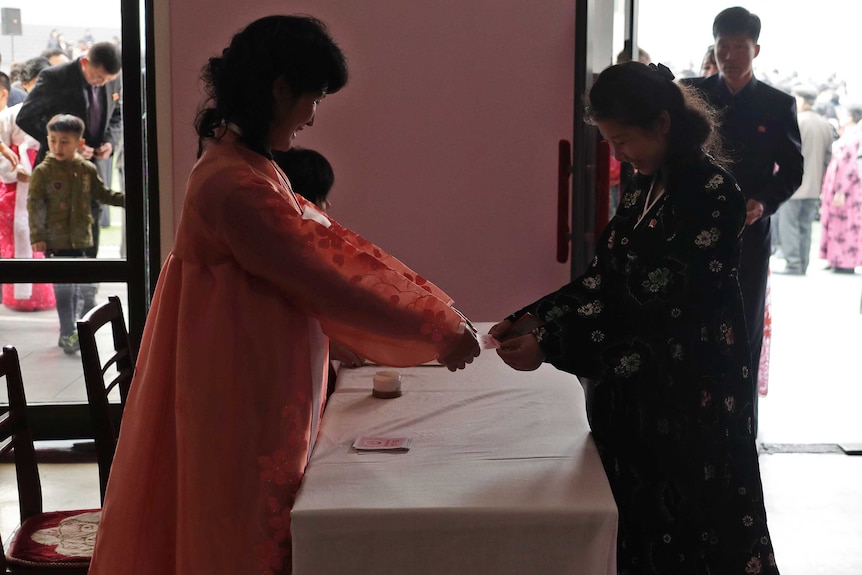 A woman receives her ballot before voting in North Korea's election.